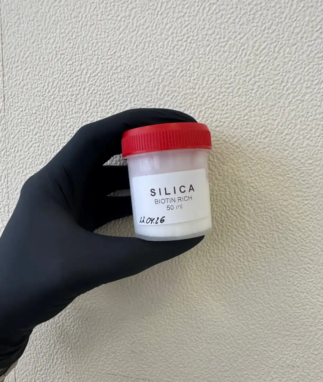 Баночка с образцом SILICA в руке в чёрной перчатке